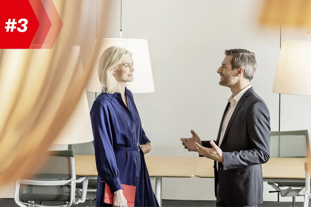 En kvinne og en mann snakker med hverandre i et konferanserom 
