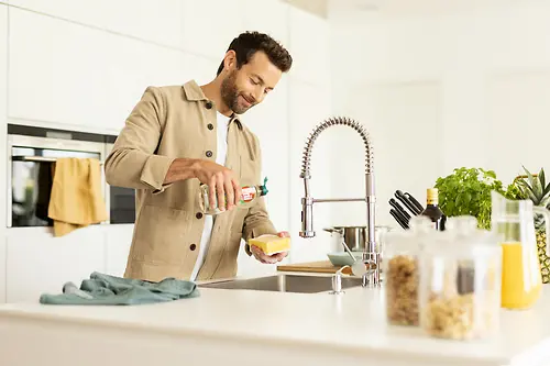 Mann på kjøkkenet tar oppvasken