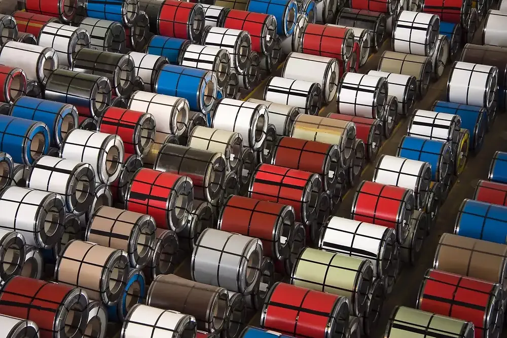 Nærbilde av stablede metallspoler i et industrilager.