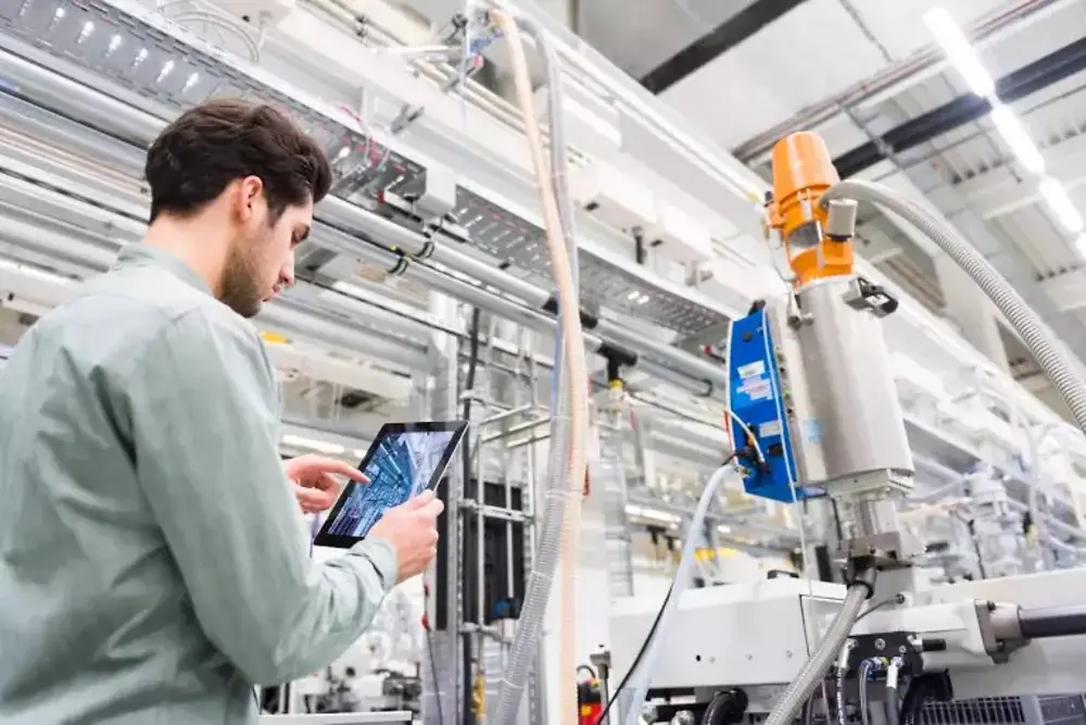 Arbeidere betjener maskiner inne i et industrielt produksjonsanlegg.